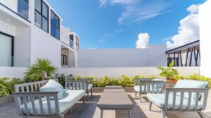 A modern outdoor patio with white furniture and potted plants. - Bright and Nice 3 Beds Close to 5th (Playa del Carmen)