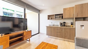 Eine moderne Küche mit Holzausbau, einer eingebauten Mikrowelle und einem großen Flachbildfernseher auf einem Holzboden.