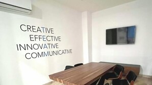 A conference room with a long wooden table, black chairs, and a wall-mounted air conditioner. - Ipana 1 Bedroom Full Equipped Oceanview Rooftop (Playa del Carmen)