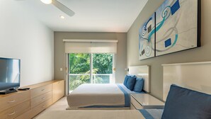 A modern bedroom with a bed, a TV, and a large window. - Bright and Stylish Ocean View Roof top Pool (Playa del Carmen)