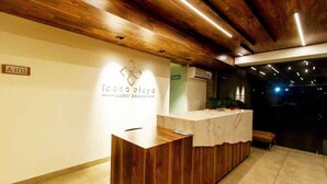 Una recepción con detalles de madera, un cartel que dice "Icono Playa Luxury Condo" y un suelo de baldosas.