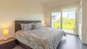 A bedroom with a large bed, a nightstand, and a view of the outdoors through a sliding glass door. - Penthouse w Private Jacuzzi Steps to 5thav Beach (Playa del Carmen)