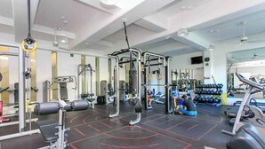 A gym with various exercise equipment, including weight machines, a squat rack, and free weights. - Penthouse w Private Jacuzzi Steps to 5thav Beach (Playa del Carmen)