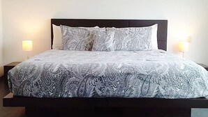 A bed with a patterned bedspread, two bedside lamps, and a dark headboard. - Penthouse w Private Jacuzzi Steps to 5thav Beach (Playa del Carmen)
