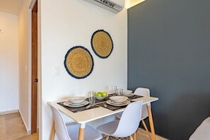 A dining area with a table set for four, two woven wall hangings, and an air conditioning unit above. - Chic new Studio w Pool Steps to Beach 5th (Playa del Carmen)