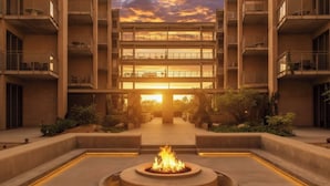 A modern building with a central courtyard featuring a fire pit, surrounded by balconies and vegetation.
