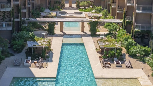 A hotel with a central pool, multiple balconies, and outdoor seating areas.
