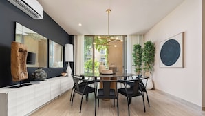 A modern dining area with a round table and chairs, a large mirror, and a potted plant.