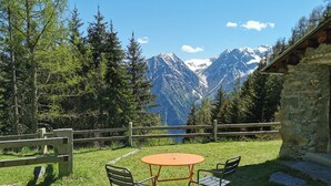 Pátio com mesa e cadeiras com vista para uma paisagem montanhosa.