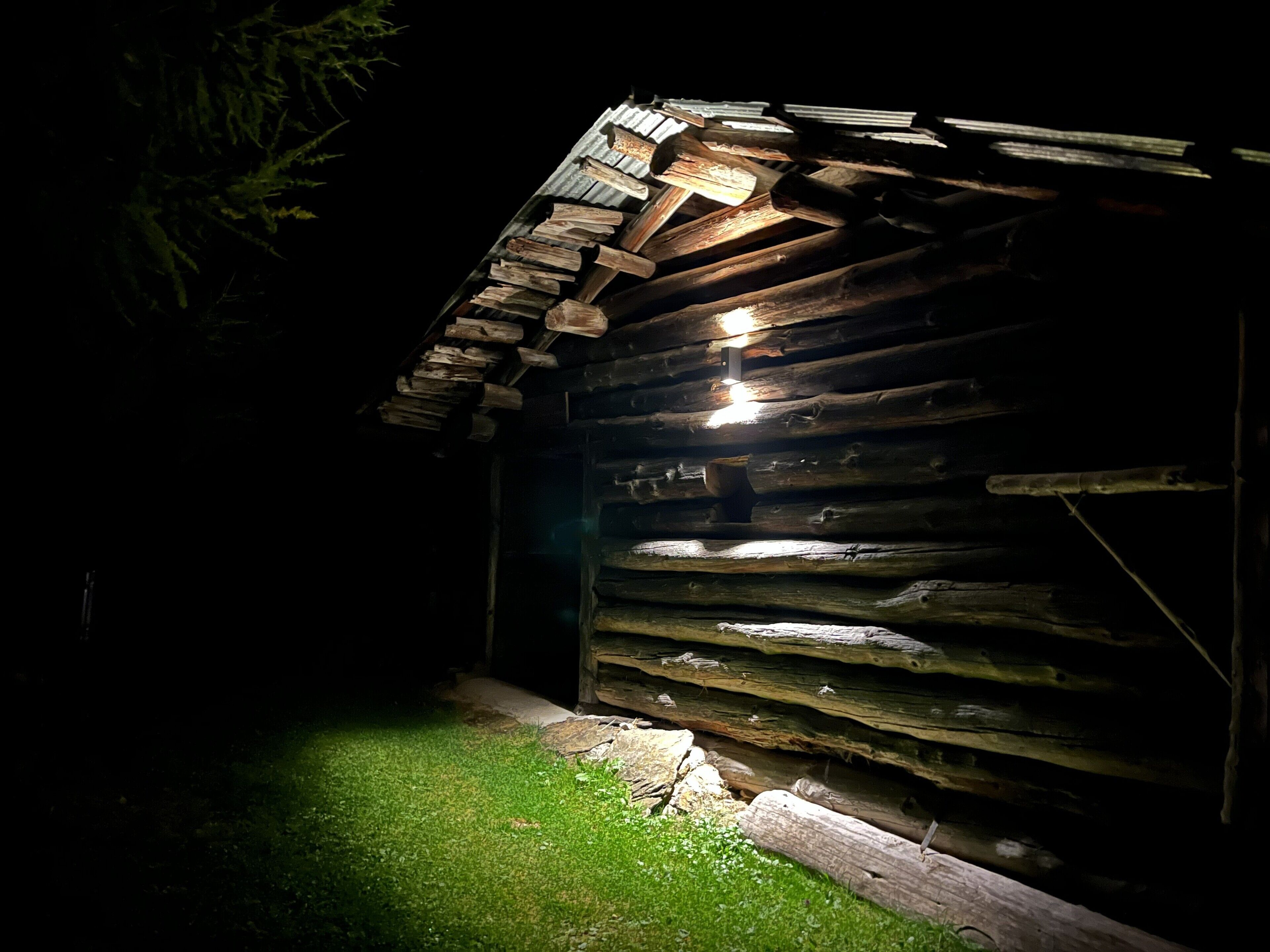 Una baita di legno rustica con tetto spiovente e un piccolo portico.