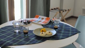 A dining table with a plaid placemat, a plate of cookies, glasses of water and coffee, and a magazine. - Sea Dream Palace 2 (Trani)