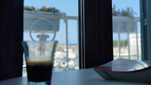 A view through a window with a glass of dark liquid, likely coffee, on a table. - Sea Dream Palace 2 (Trani)