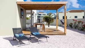 A covered outdoor seating area with two lounge chairs and a wooden pergola. - Casa Monrel, Mambo Beach (Willemstad)