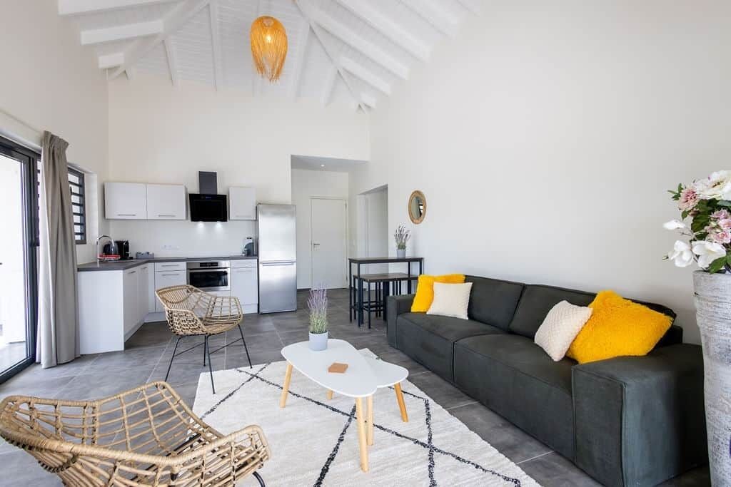 A modern living room with a sofa, coffee table, and wicker chairs.