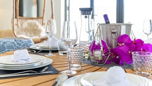 A dining table set with plates, cutlery, and glasses, a wine bottle, and a bucket.