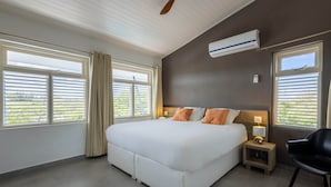 A modern bedroom with a large bed, two bedside tables, a ceiling fan, and a window with blinds.
