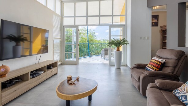 A modern living room with a large TV, wooden coffee table, and a comfortable sofa.