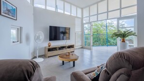 A spacious living room with a large TV, wooden coffee table, and comfortable seating.