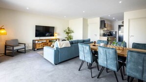 Una sala de estar moderna con sofá, televisión, mesa de comedor y sillas.