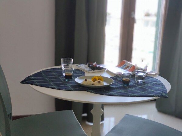A round table with a plaid placemat, a plate with food, and two glasses of a dark beverage.