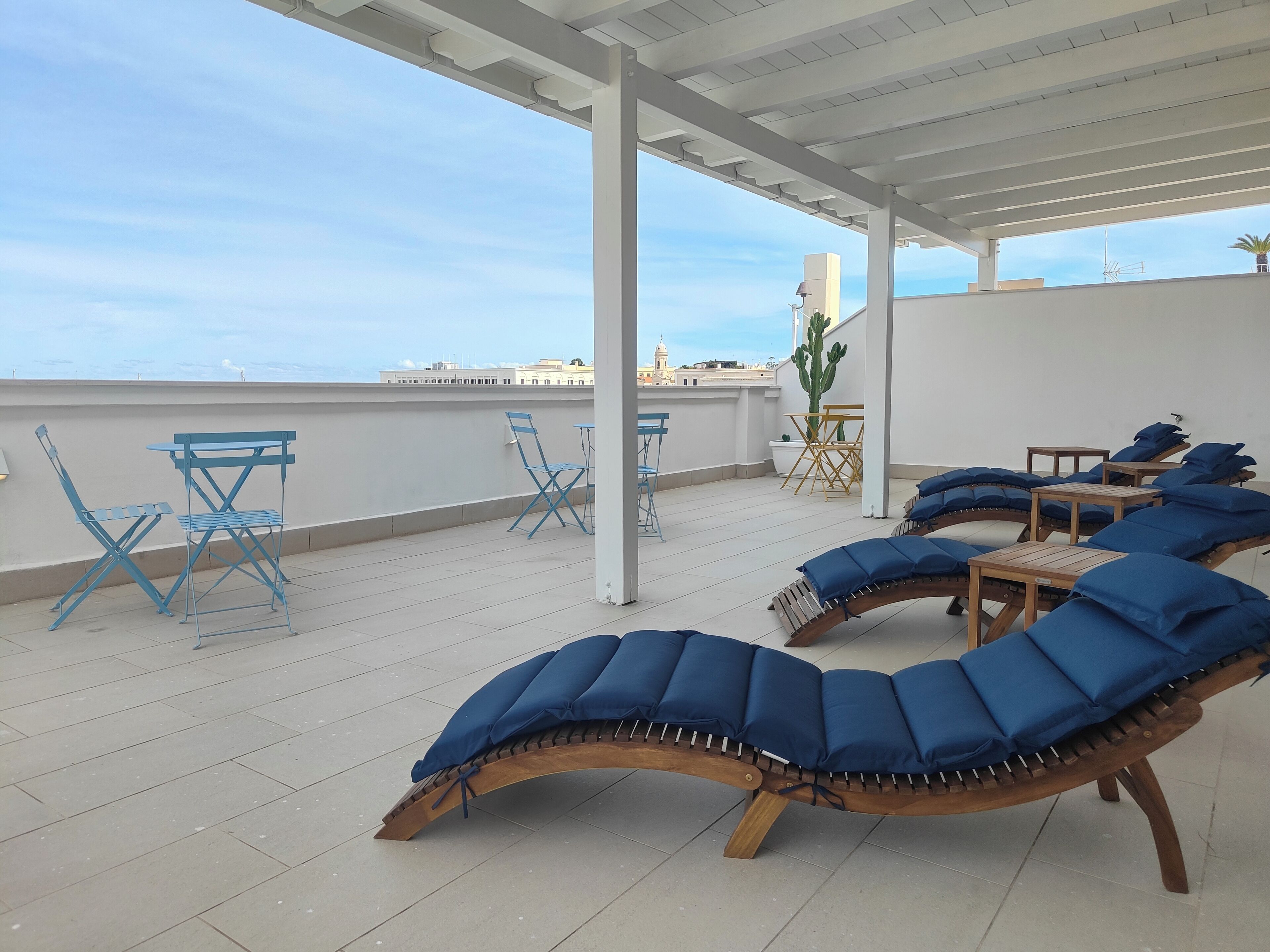 Eine Dachterrasse mit Liegestühlen, Klappstühlen und einem Tisch.