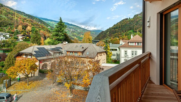 A balcony with a view of a valley, houses, and a tree with autumn leaves. - 305B Apartments No 10 (Ponte Gardena)