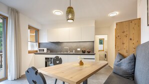 A modern kitchen with white cabinets, a wooden dining table, and a gray sofa. - 305B Apartments No 10 (Ponte Gardena)