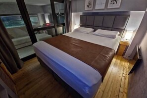Une chambre d’hôtel avec un lit, une fenêtre, un mur orné de tableaux encadrés et un plancher en bois.