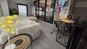 A modern hotel room with a bed, a desk, a chair, a large window, and a painting of the Eiffel Tower.