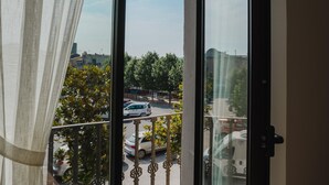 A view from a balcony with a metal railing, looking out onto a street with parked cars and trees. - Torre dels Bous Apartment 1-A (Hostalric)