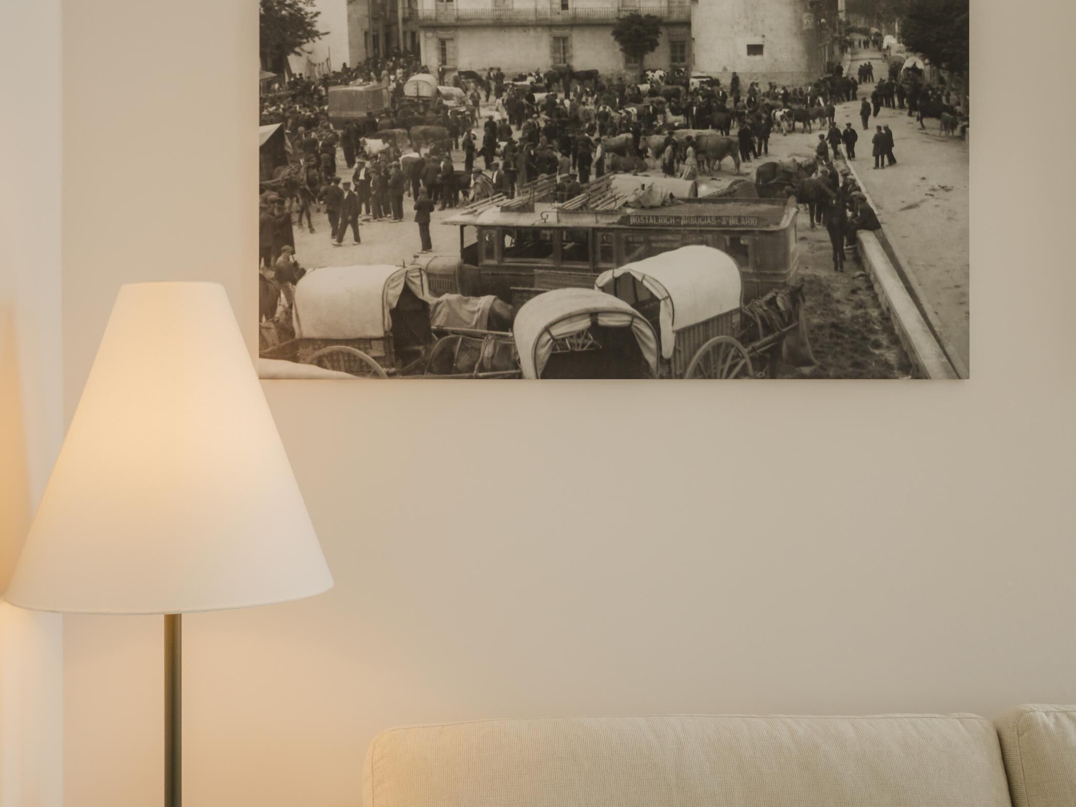 Fotografía en blanco y negro de una calle concurrida, con carruajes tirados por caballos y gente.