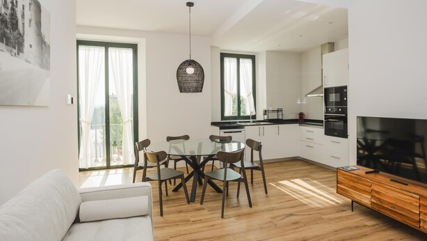 A modern apartment with a dining area, kitchen, and living room. - Torre dels Bous Apartment 1-A (Hostalric)