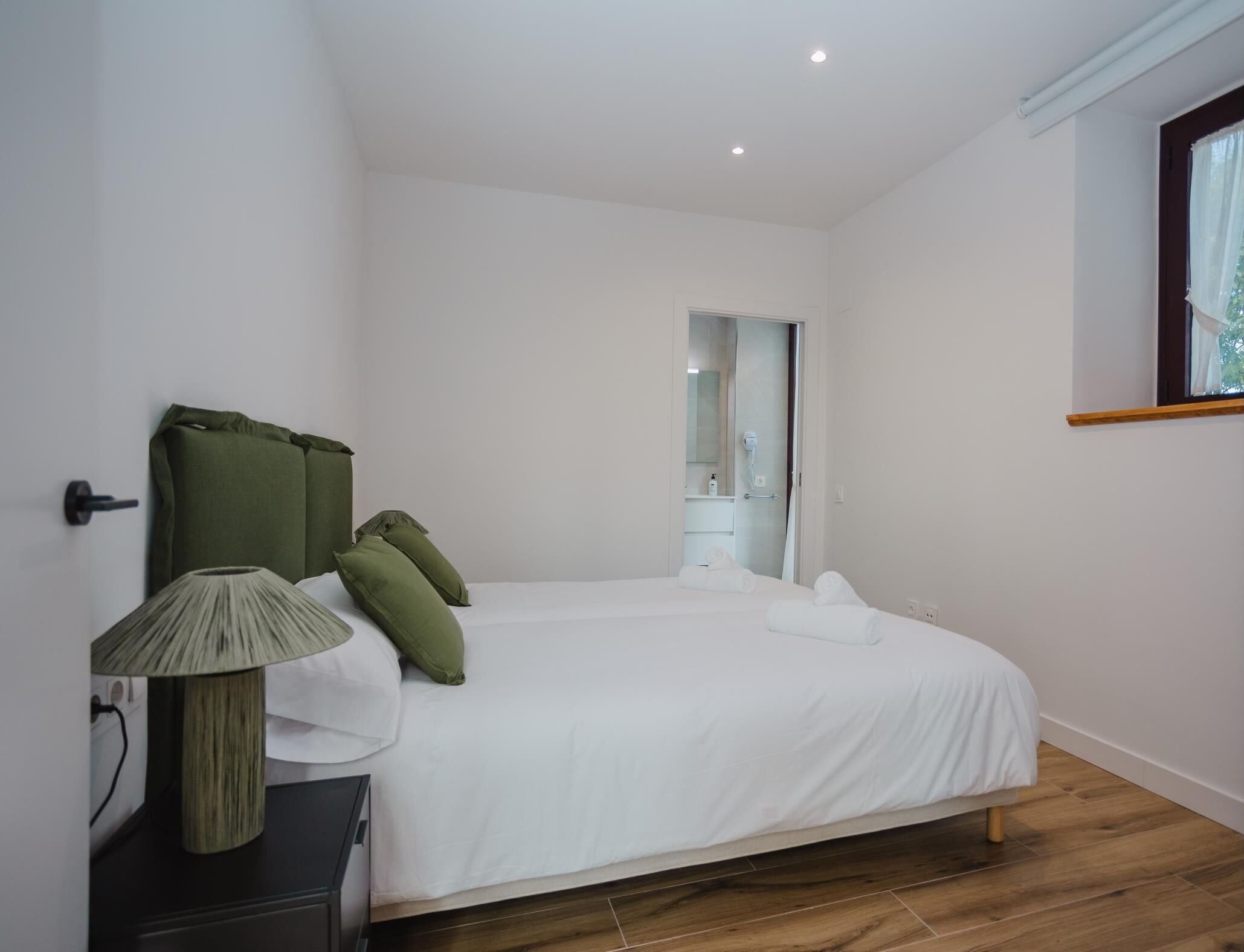 A bedroom with a bed, a bedside table, a lamp, and a mirror.