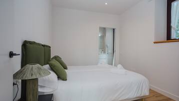 A bedroom with a bed, a bedside table, a lamp, and a mirror.