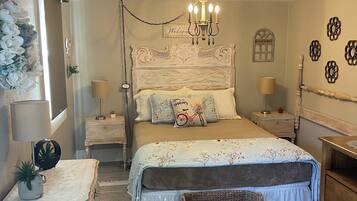 Une chambre à coucher avec un lit, des tables de chevet, un lustre, une pancarte de bienvenue et un mur décoratif.