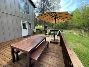 Une terrasse avec une table et des chaises, une rambarde en bois et un grand parasol.