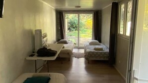 A compact room with two beds, a small table, and a window.
