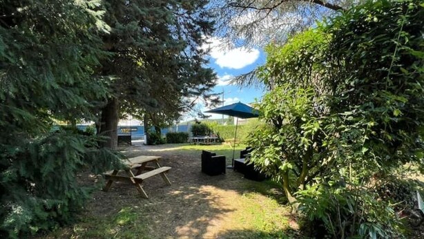 A garden area with a picnic table, a blue umbrella, and a bench.