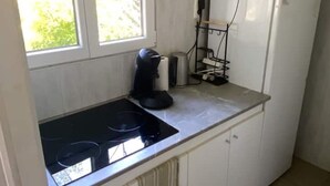 A small kitchen with a black stovetop, white cabinets, and a window providing natural light.