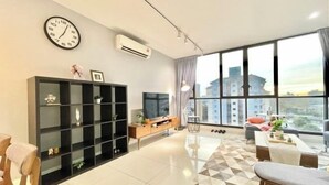 A modern living room with a large window, a black entertainment unit, and a tiled floor.