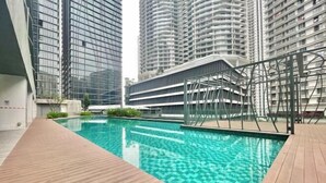 A modern building with a swimming pool, surrounded by high-rise residential buildings.