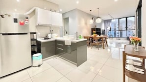 A modern kitchen with a central island, white cabinets, and a dining area with a table and chairs.