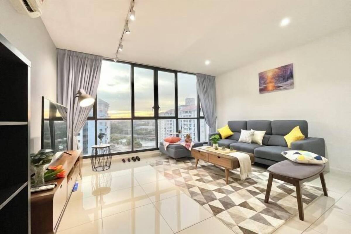 A modern living room with a sofa, coffee table, and a view of the city through large windows.