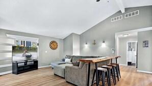 A modern living room with a grey sofa, a wooden coffee table, and a TV displaying a speedboat. - Greens and Gators For 20ppl (Lake Ozark)