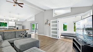 A modern living room with a grey sectional sofa, a flat-screen TV, and a ceiling fan. - Greens and Gators For 20ppl (Lake Ozark)