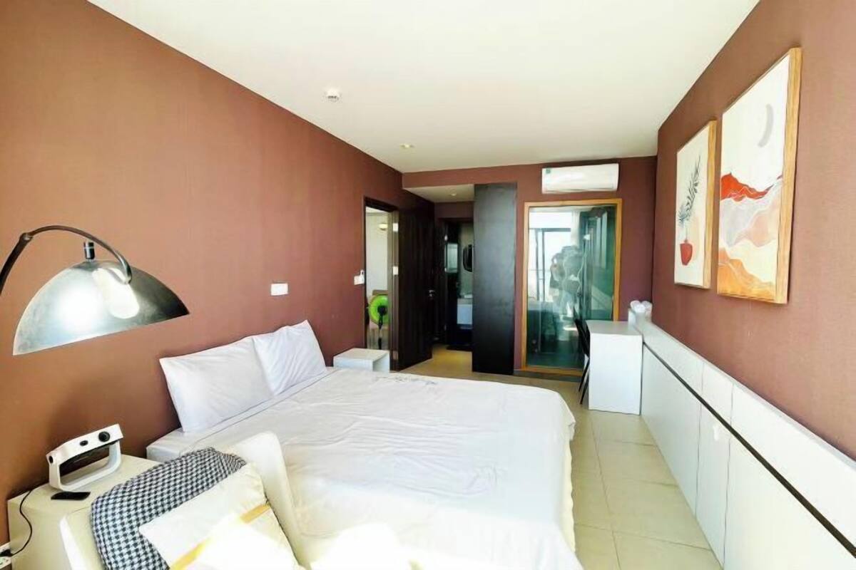 Ein Hotelzimmer mit einem großen Bett, einem Schreibtisch, einem Sessel, einer Lampe und Bildern an den Wänden.