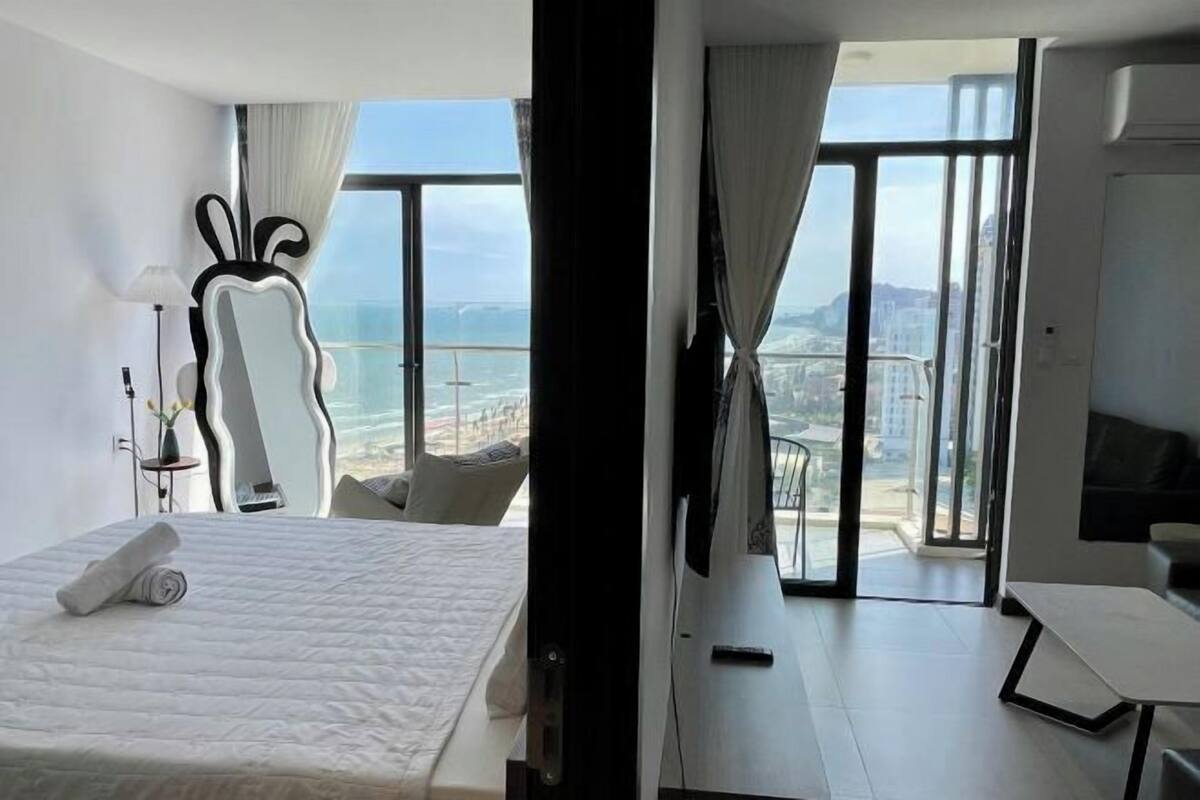 Ein modernes Hotelzimmer mit einem großen Bett, einer Sitzecke mit Tisch und einem Balkon mit Blick auf die Stadt.