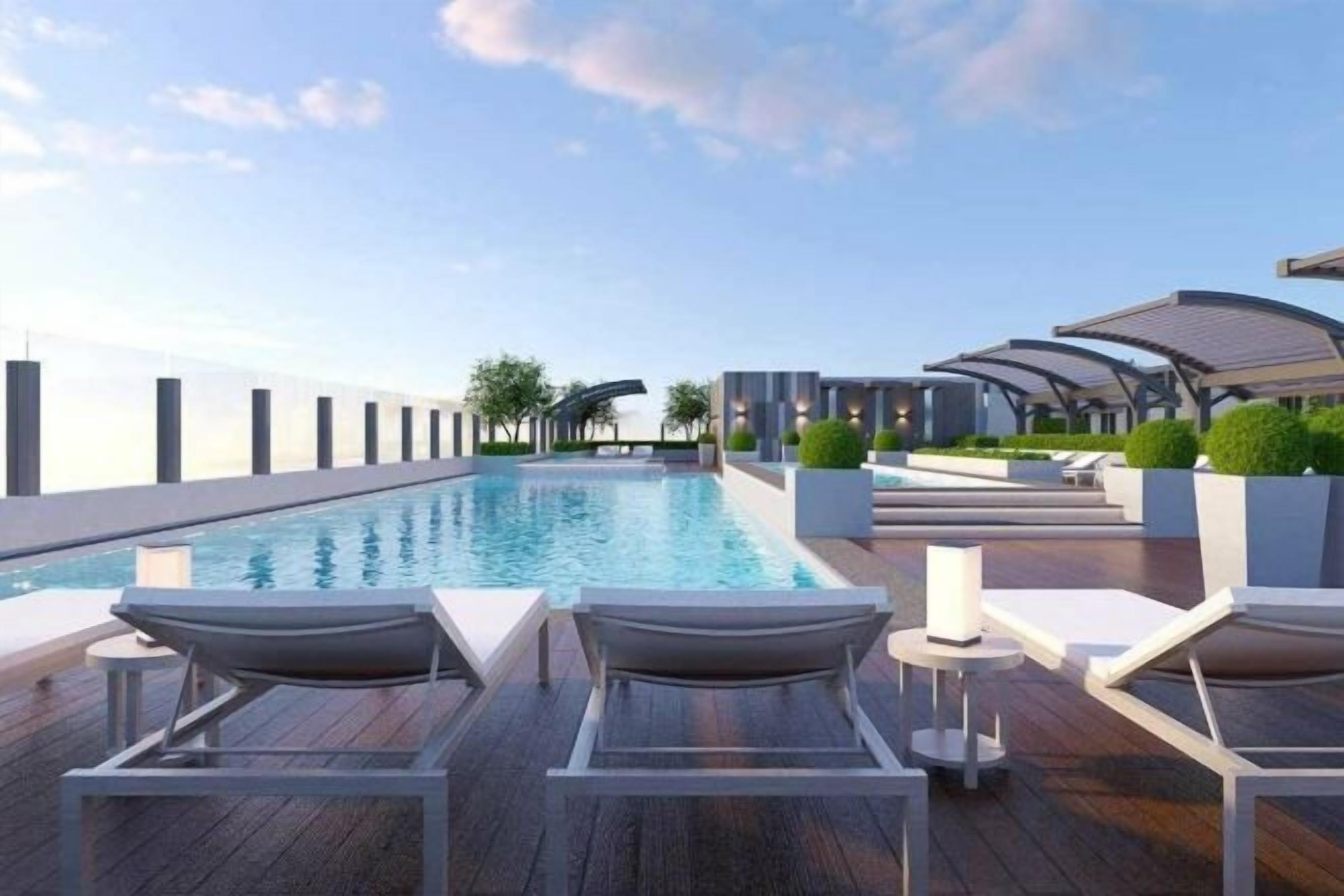 Un espace piscine aménagé sur le toit, avec des chaises longues et une vue sur le panorama urbain.