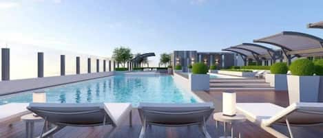 A rooftop pool area with lounge chairs and a view of the city skyline.
