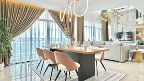A modern dining area with a central island, chairs, and a sofa in the background. - Molek Regency By Stayrene (Plentong)